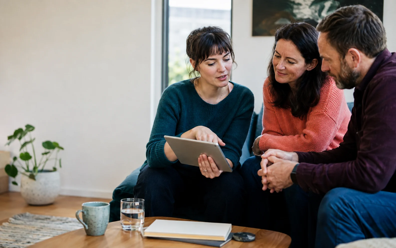 Three people sharing a tablet during a care conversation.